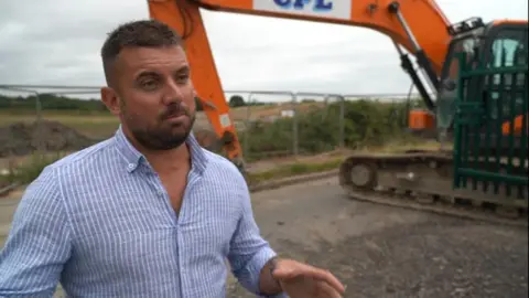 Jack Raison standing in front of a digger