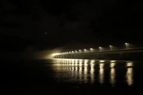 Aonghus Marshall The Tay Road Bridge taken while dark outside. The lights from the bridge are reflected on the river. 