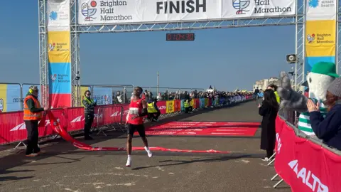 BBC/ALISON FERNS Seyfu Jamaal crossing the finishing line of the Brighton Half Marathon.