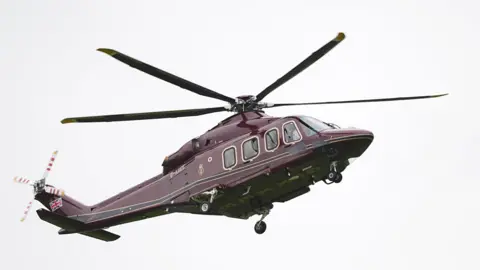 PA Media A dark purple-coloured helicopter in the sky.
