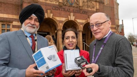 Councillors and a librarian hold blood pressure monitors