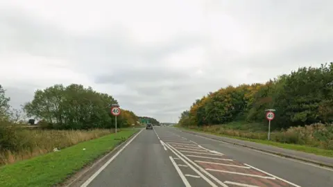 Road with a 40mph speed limit sign and trees either side
