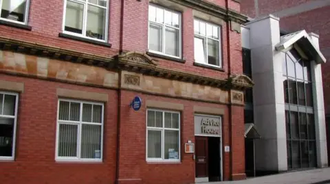Citizens Advice Staffordshire North and Stoke-on-Trent A red-brick Victorian building on two stories, with Advice House written above the main entrance. The picture is taking from the opposing pavement. A modern glazed entrance to a grey building is adjacent on the right.