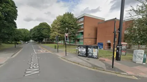 A four-storey block of flats surrounded by trees