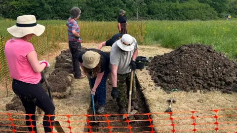 RWB Environment Trust People dressed in summery clothes digging in an enclosed space. 