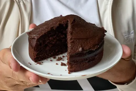 A chocolate cake on a plate with a big slice cut out