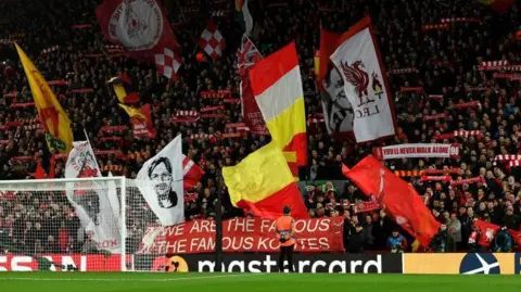 Getty Images Fans waving large flags in the stands ahead of the LFC and Atletico Madrid match kicking off