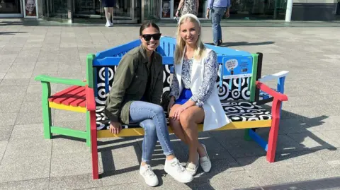 Arts University Bournemouth Two young women sit on a colourful bench