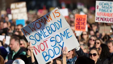 Maryam Majd/Getty Images Women hold up placards as they take part in a demonstration in support of Actress Collien Fernandes