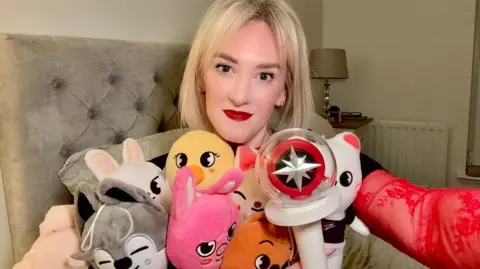 A blonde woman holding stuffed toys