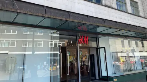 Pete Cooper/ BBC A glass store frontage with the red H&M sign above the two glass open doors.