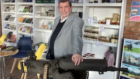 Lee Evans standing by a Maxim machine gun