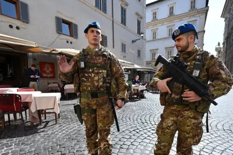 AFP Soldiers with guns walk through a street in Rome