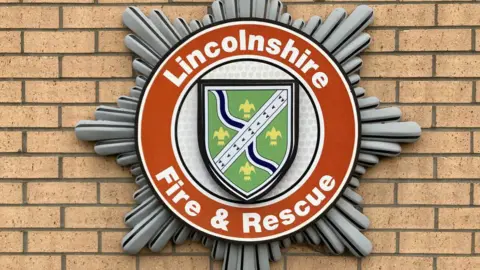 A close-up of Lincolnshire Fire and Rescue's logo, fixed to a brick wall.