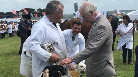 Sheep farmer holding trophy talking to King Charles 