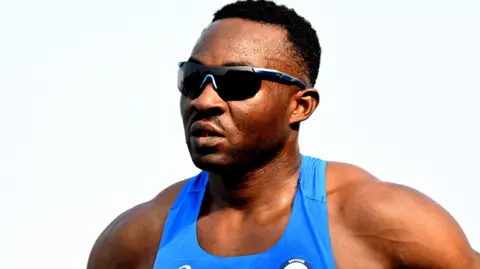 Getty Images Guillaume Junior Atangana wearing a blue running vest and sunglasses