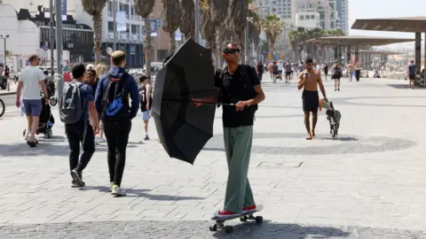 JACK GUEZ/AFP A man rides a skateboard along the beach in Tel Aviv on April 19, 2024