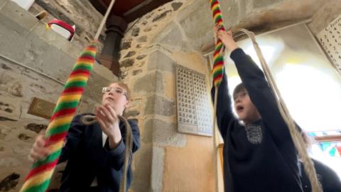 Children pulling the ropes to ring church bells 