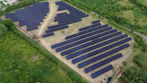 Premier Foods A large solar farm with several rows of solar panels with trees around the edge. 