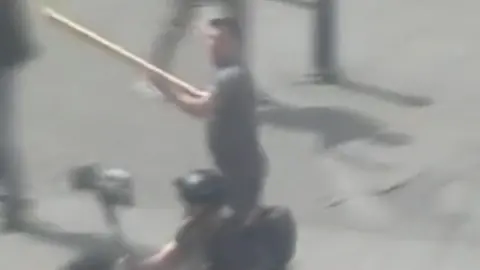 Man holding plank of wood during disorder