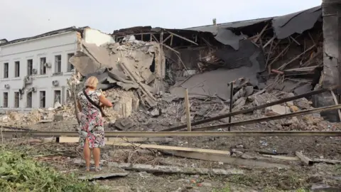 Getty Images Seorang wanita melihat bangunan yang rusak akibat serangan rudal Rusia di ibu kota Ukraina, Kyiv, pada hari Senin.