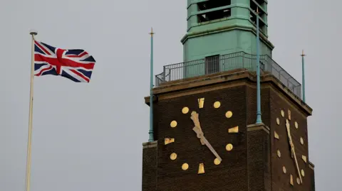 Norwich City Hall PAMedia clock tower showing the clock face at 11:25 am and the Union Jack flag.