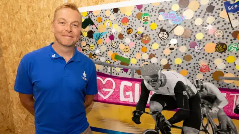 Sir Chris Hoy beside a mural created by artists at charity Glasgow The Caring City to celebrate the impact of National Lottery funding. 