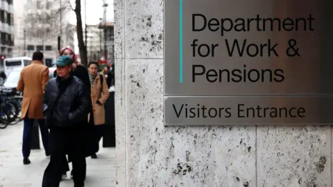 EPA A view of the entrance to the DWP building in London, with a metal sign reading Department for Work and Pensions Visitors Entrance.