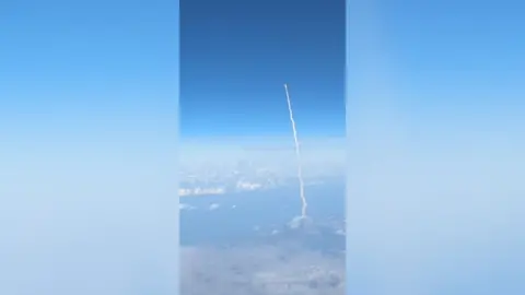 The view from a commercial flight of the Artemis II mission spacecraft in the sky during blast off.