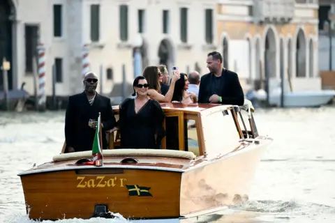 Getty Images US manager Corey Gamble and US television personality Kris Jenner in Venice, Italy, for the wedding of Jeff Bezos and Lauren Sanchez. They are both wearing black outfits and sunglasses. 