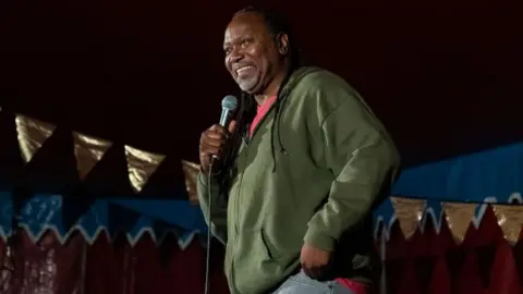 Getty Images Reginald D Hunter performs on the soap box stage during Kendal Calling 2019 at Lowther Deer Park on July 27, 2019