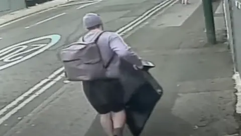 Nottinghamshire Police A CCTV image of a man carrying a large flat-screen TV. He is seen from the back and is wearing a grey jumper, hat and has a grey rucksack on his back. He is wearing black shorts.