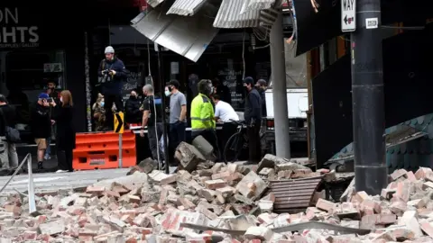 Getty Images Rubble on a street next to bystanders