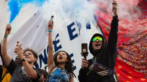 Getty Images People holding phones aloft gather during an election night in Paris, France.