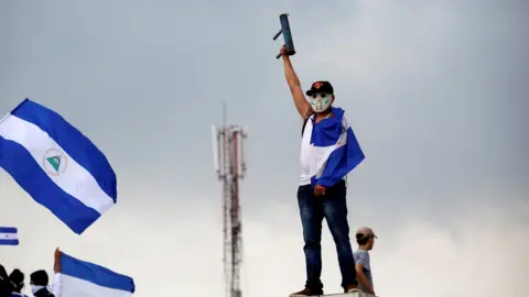 Reuters A man wearing a baseball cap, hockey mask, and draped in the national flag raises his home-made mortar in victorious salute in Managua, Nicaragua May 26, 2018.