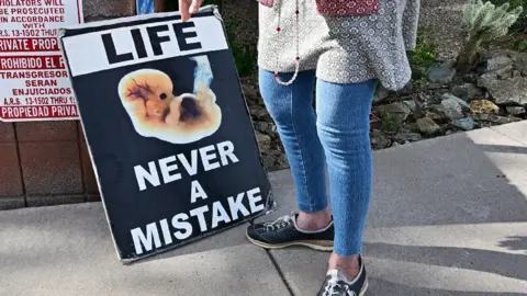 Getty Images A woman holds a sign reading: "Life: Never a mistake"