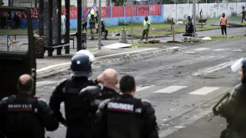 THEO ROUBY/AFP French gendarmes stand guard near independantists at the entrance of the Riviere Salee disctrict, in Noumea, France's Pacific territory of New Caledonia, on May 29, 2024