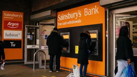 Getty Images People using ATMs under a Sainsbury's Bank sign