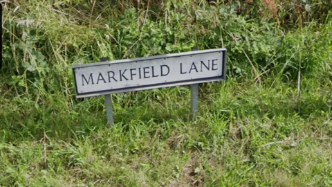 Google A street sign saying Markfield Lane with grass around the sign