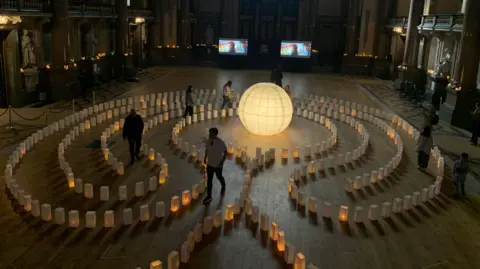 Overhead view of people walking through an art installation of paper lanterns in St George's Hall.