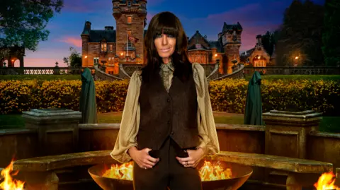 BBC/Studio Lambert/Cody Burridge/Matt Burlem Claudia Winkleman poses outside the Traitors castle in a promotional image for series four