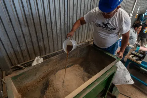 Fritz Pinnow a worker pours meat fat into a mixture that will become food for dogs