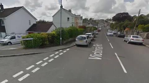 Google Street View image of the junction of Morleigh Close and Victoria Road in St Austell, with cars parked on both sides of the road.