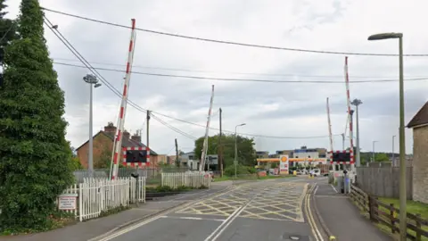 Google A google maps screenshot of the london road rail crossing. It is on a single carriageway, and has four separate barriers, as well as lights. Further down the road is a petrol station.