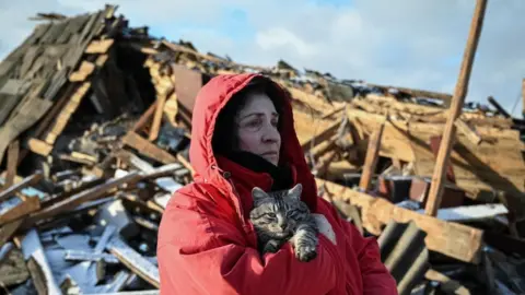 Reuters A lone woman holds a cat, surrounded by debris a day after a Russian strike, Ukraine: Resident Svitlana Vlasyk hugs her cat and looks at her house destroyed by yesterday's Russian missile strike, amid Russia's attack on Ukraine, in Chernihiv, Ukraine January 4, 2025