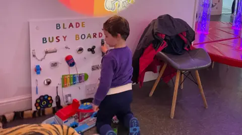 Supplied A young boy playing with a sensory board.