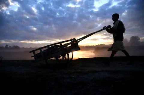 AFP A man pushes his cart to go to work early in the morning during sunrise as clouds gather on the sky in the outskirt of Guwahati in Assam, India on Friday, December 21, 2018