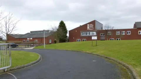 The outside of James Calvert Spence College, which is a brick building with a grassy bank in front of it.