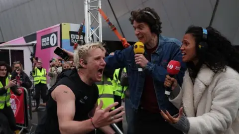 Jamie Laing wearing black running vest crosses the finish line