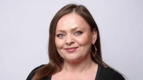 A photograph of a woman with dark hair looking at the camera